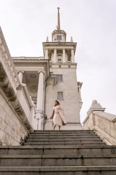 woman in elegant coat and hat against an intricate architectural backdrop, harmoniously blending modern fashion with historical allure. The soft daylight adds to its timeless appeal