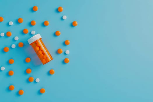 Medicine pills spilled from plastic pill bottle, on blue background. Medicine creative concepts. Flat lay top view, copy space.