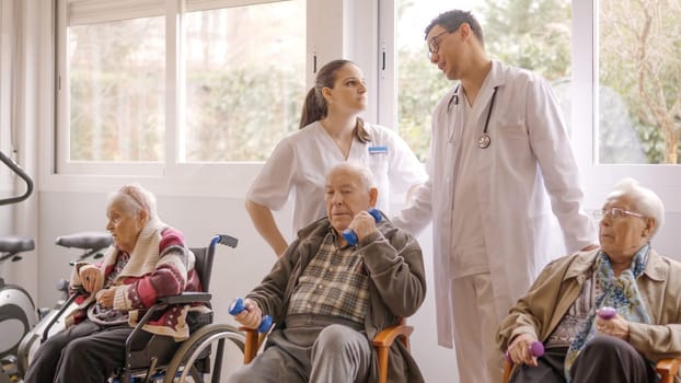 Two distracted doctors talking while senior people exercising in geriatric