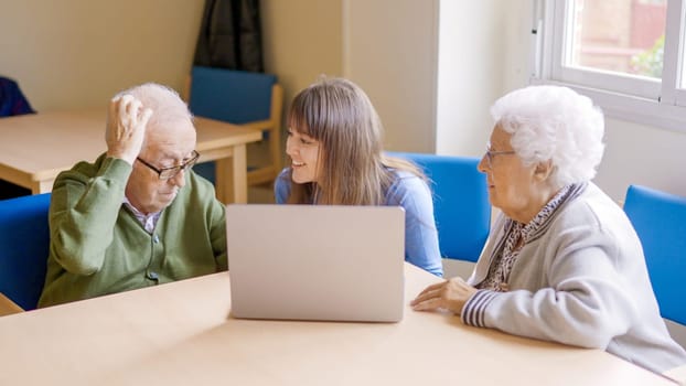 Granddaughter helping to her grandparents to use the laptop. Her grandfather has a hard time understanding him