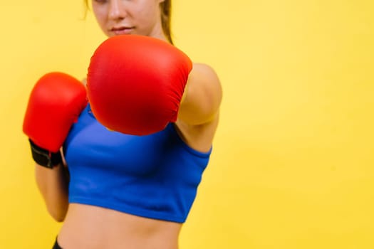 Woman boxer in gloves training on a grey and yellow background