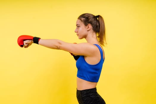 Woman boxer in gloves training on a grey and yellow background