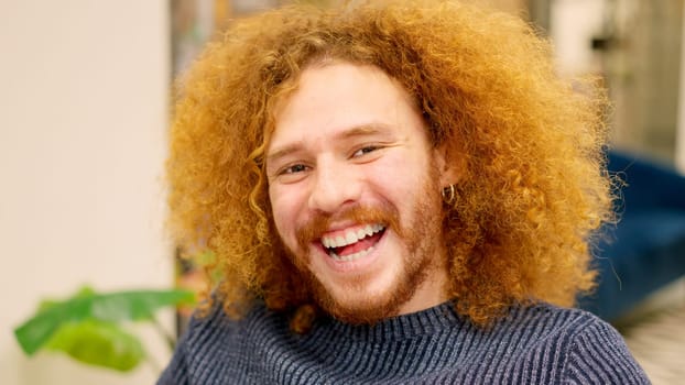 A man with curly hair smiling at camera in a coworking