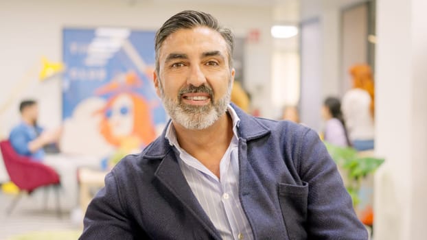 A mature employee smiling at camera in coworking