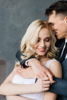 Cute wedding couple in the interior of a classic studio. They kiss and hug each other.