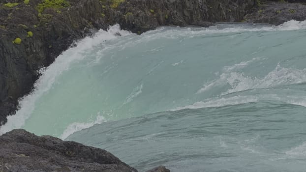 Captivating slow-mo of a turquoise glacier waterfall in a canyon during gentle rain.