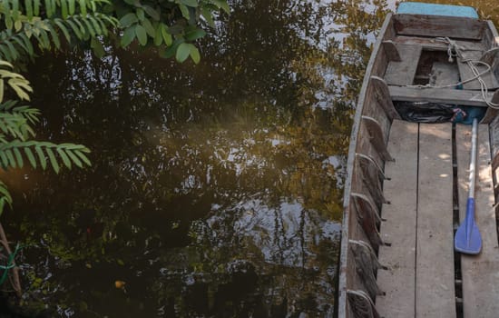 Rowboat moored to along the canal amongst trees and water in rural landscape. Space for text, Selective focus.