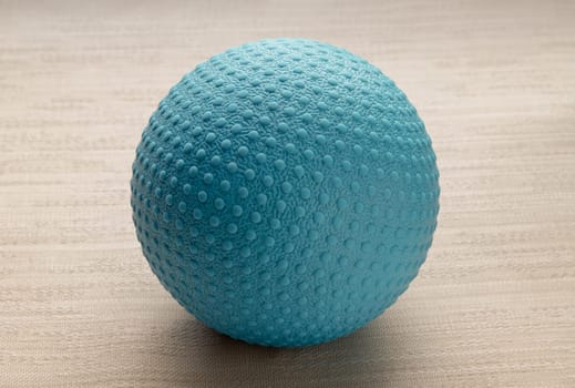 Lacrosse massage ball on sofa cushions. Blue rubber lacrosse ball, Spherical ball, Space for text, Selective focus.