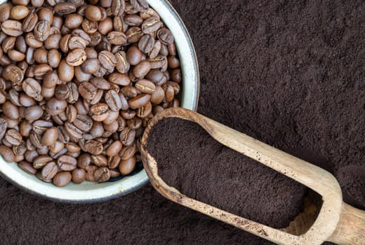 Coffee beans in round bowl with Coffee powder in wooden scoop with Coffee powder background. lternative coffee for living life, Coffee concept, Space for text, Selective focus.