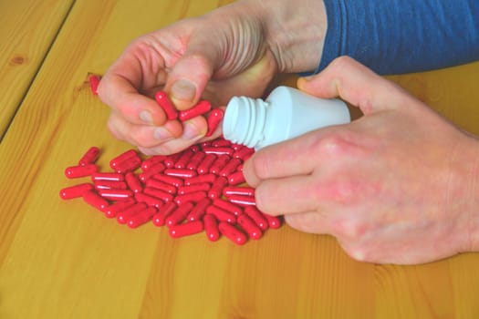 Man hand holding drug medicine bottle, spilling pills out of bottle.
