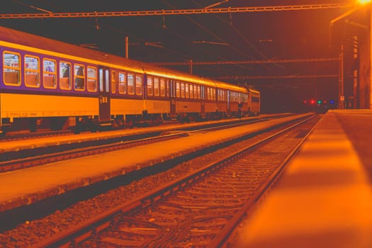 White and blue train standing at a small roofless train station at night in the Czech Republic. European train.