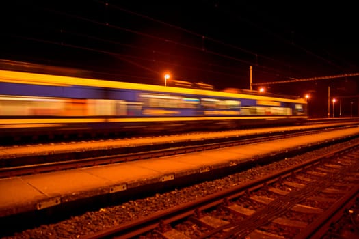 Passenger train on railroad tracks at night Blurred motion.