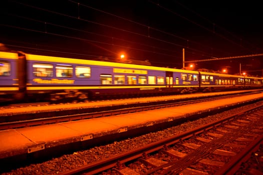 White and blue train standing at a small roofless train station at night in the Czech Republic. European train.