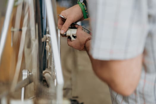 Cropped shot of male mechanic working in bicycle workshop. Bike service, repair and upgrade