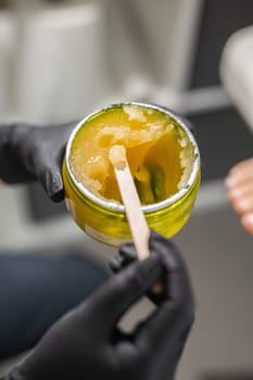 Orange body scrub with sugar and oil in glass jar in female hand. Homemade cosmetic for peeling and spa care. Copy space and empty place for advertising.