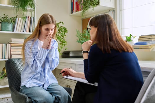 Sad upset young teenage female patient talking to professional mental therapist. Teenager girl high school college student in therapy with psychologist psychotherapist counselor. Psychological health