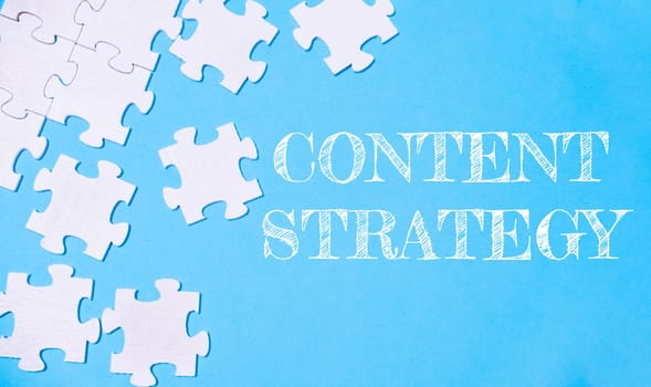 A jigsaw puzzle with the word content strategy written on it. The puzzle pieces are scattered across the image, creating a sense of disarray and complexity