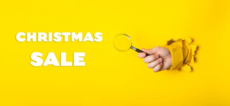 A person holding a magnifying glass with the words Christmas Sale written below. The image has a festive and playful mood