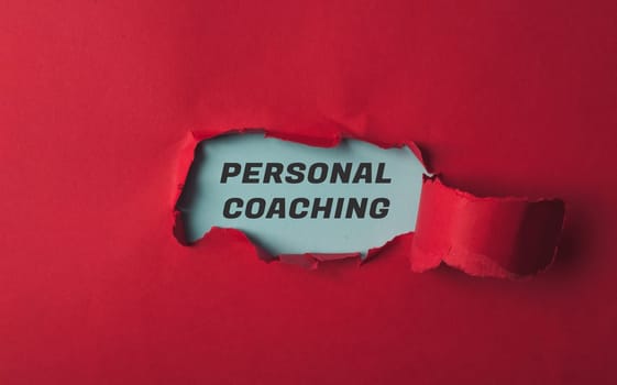 A red piece of paper with the word personal coaching written in black. The paper is torn open, revealing the word "personal" in white