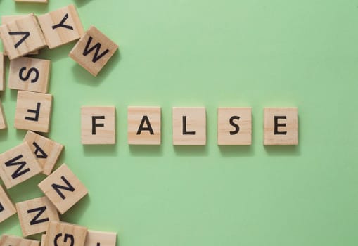 A jumble of wooden letters spell out the word false. The letters are scattered across the image, with some overlapping each other. Scene is one of confusion and disarray