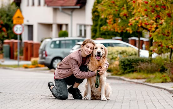 Preteen teen girl wear on golden retriever dog lace outdoors. Pretty kid child with purebred pet doggy walking at street