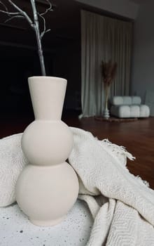 A large beige vase as part of the decor in a large spacious room. High quality photo