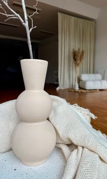 A large beige vase as part of the decor in a large spacious room. High quality photo