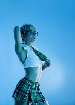 Sexy girl in an erotic school plaid skirt costume from a sex shop in blue neon light on a copy paste background