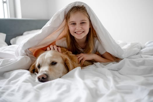 Girl Lies Under Blanket With Her Golden Retriever Dog