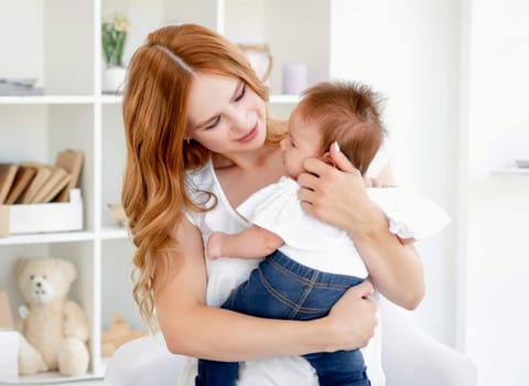 Young mother hugging cute baby at home