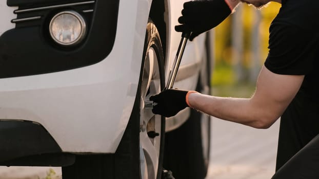 Mechanic Repairs Car, Working Diligently, Unscrewing Wheel Bolt With Wrench