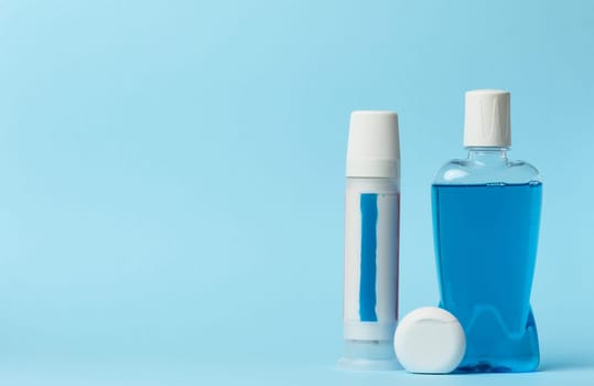 Mouthwash, toothpaste tube, dental floss on a blue background, oral hygien. Copy space
