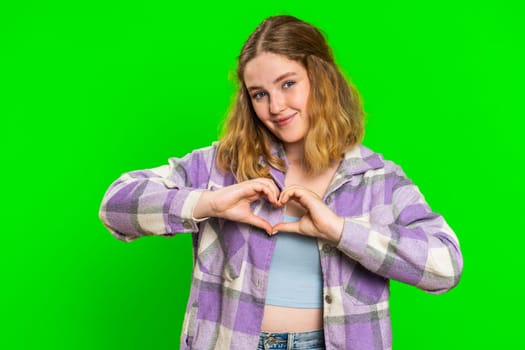 Woman in love. Smiling attractive woman makes heart gesture demonstrates love sign expresses good positive feelings and sympathy. Pretty redhead young girl isolated on chroma key wall background