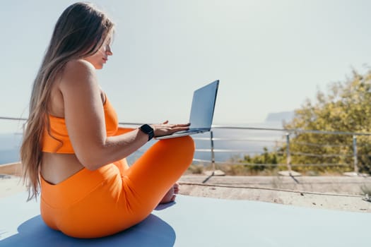 Digital nomad, Business woman working on laptop by the sea. Pretty lady typing on computer by the sea at sunset, makes a business transaction online from a distance. Freelance, remote work on vacation