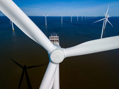 A wind farm off the coast of the Netherlands in Flevoland, harnesses the power of the ocean breeze with towering turbines on the horizon. windmill turbines green energy in the ocean