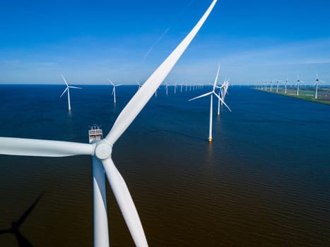 A group of picturesque windmills from the Netherlands Flevoland region gracefully float atop a tranquil body of water on a beautiful Spring day. windmill turbines green energy in the ocean