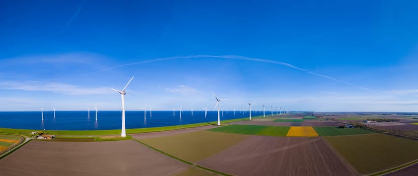 A mesmerizing aerial view capturing a wind farm near the ocean in the Netherlands Flevoland during the vibrant season of Spring.