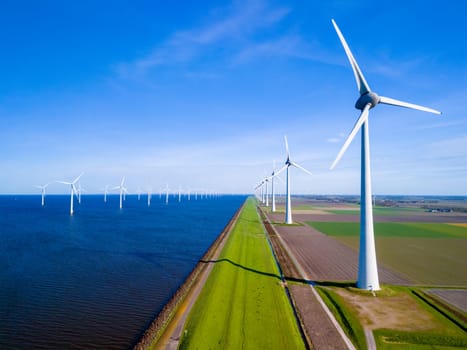 A row of elegant wind turbines stand tall by a vast body of water in the Netherlands Flevoland, reflecting the harmony between nature and renewable energy.