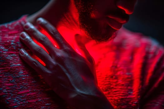 Intense close-up shot of a man touching his chest, accented by striking red light. Symbolic of emotions or health awareness.