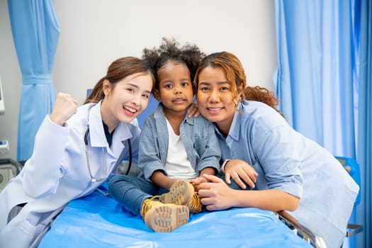 Beautiful doctor woman stay together and close with little girl sit on hospital bed with her mother in emergency room.