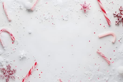 Christmas postcard backdrop with candy canes, snowflakes, and copyspace for holiday text. White and red festive decoration concept.