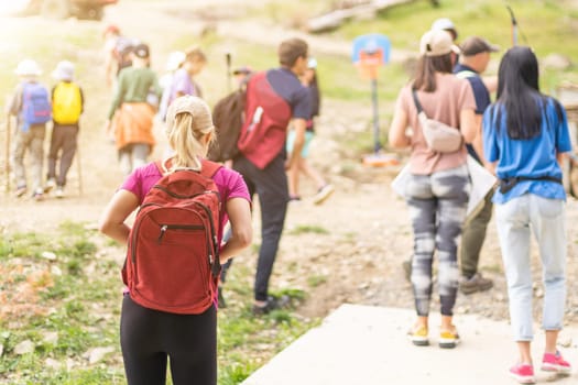 Group of hikers with backpacks climbing up mountains.