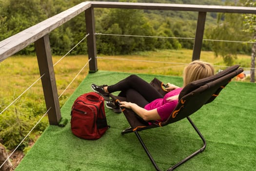 woman hiker resting after day of hike. Tourist enjoying landscape of mountain hills and morning sky. Concept of travelling, hiking