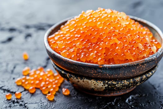 Close-up of salmon caviar in rustic ceramic bowl on dark slate surface. Orange roe texture, gourmet food concept.