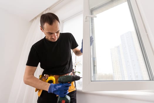 Handsome young man installing bay window in a new house construction site. High quality photo