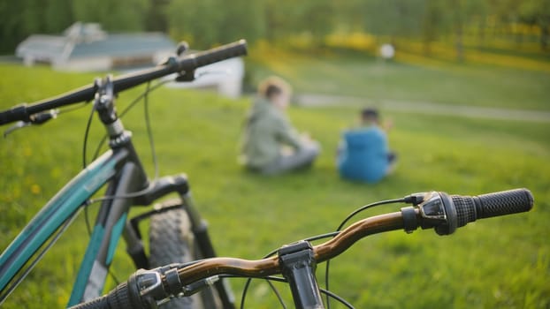 Two boys sitting in the park in front of their bicycles