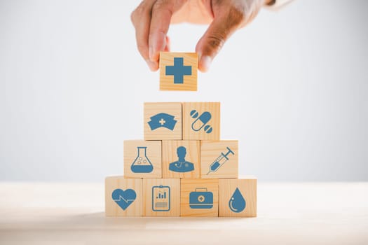 Captured moment, Hand gripping a wooden block showcasing healthcare and medical icons. Depicting safety, health, and family care, symbolizing pharmacy and heart well-being. health care concept