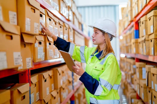 Side view young warehouse worker hold tablet and check product by point on label of the box on shelves.