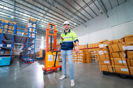 Caucasian warehouse worker man action of pull cargo small truck that carry product boxes in area of  workplace.