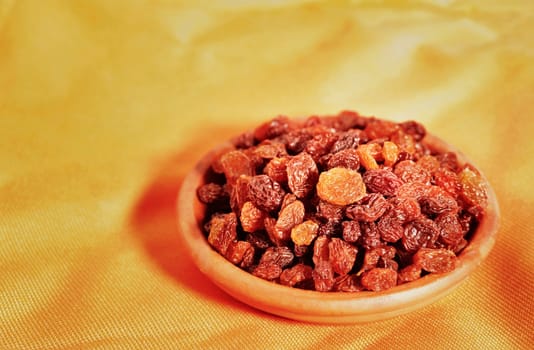  Bunch of raisins in  bowl on colored background  , dried grape fruit eating raw or used in cooking